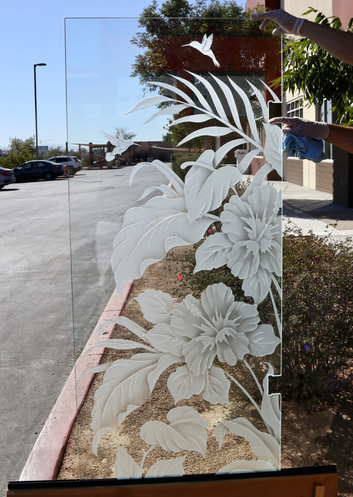 Carved hibiscus and anthurium etched glass panel with deep sandblasted floral design and privacy frosting