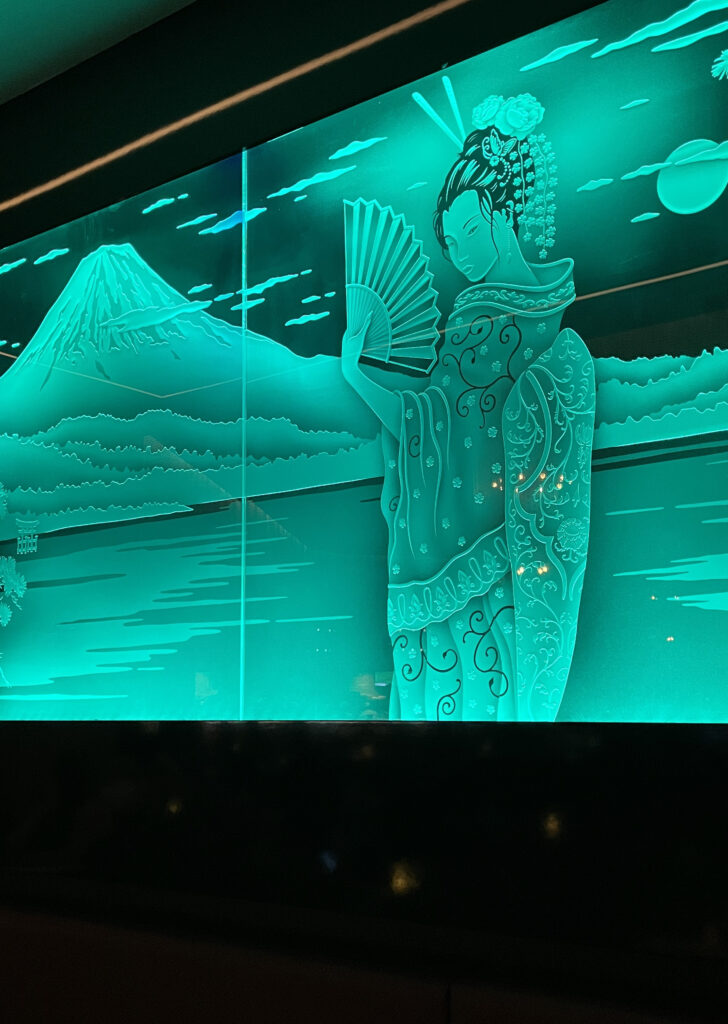 Backlit etched glass panel depicting a traditional geisha with Mount Fuji, custom architectural glass art