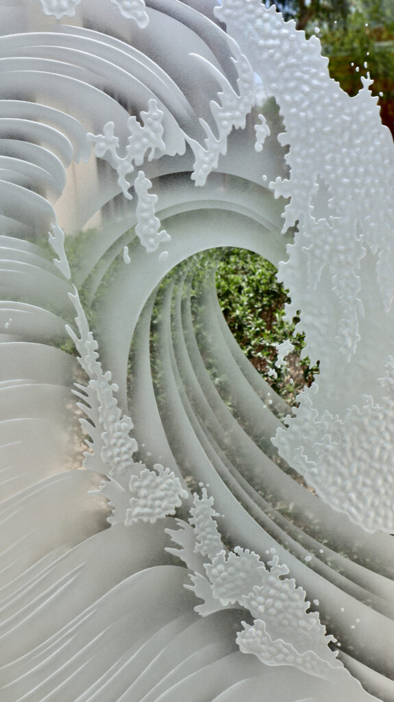 Close-up of Curl wave design on 3D carved clear glass with semi-private privacy and deep layered sandblast carving.