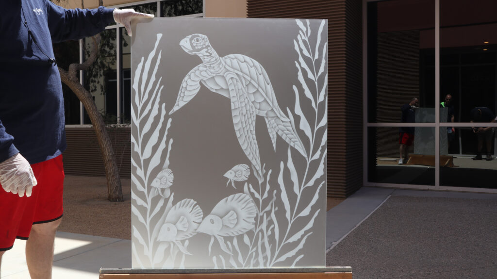 Decorative sea turtle and tropical fish design sandblasted on ultra-clear low-iron glass showing bright white frosted detail and a clean neutral appearance