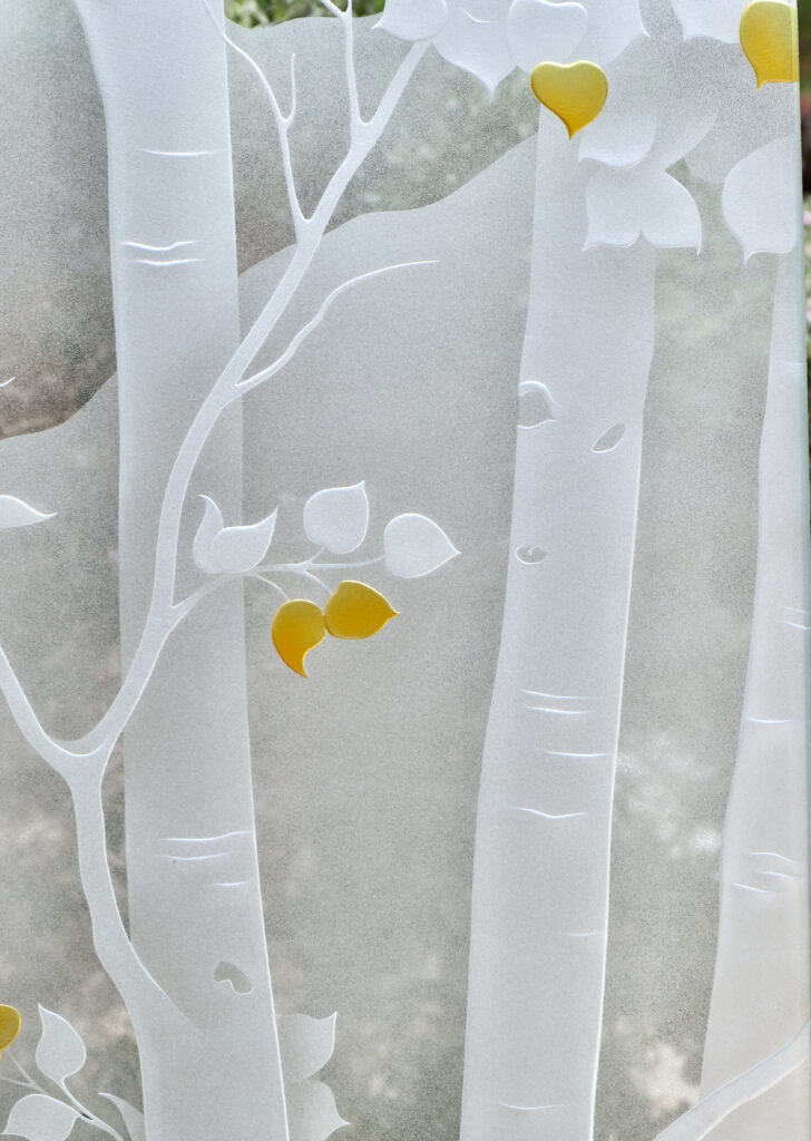 Close-up of Birch in the Rockies colored front door showing carved birch trunks and hand-painted leaf details on frosted glass.