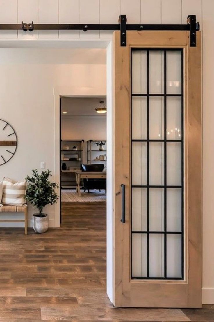 Wood-framed sliding barn door with divided glass panels in a modern farmhouse interior