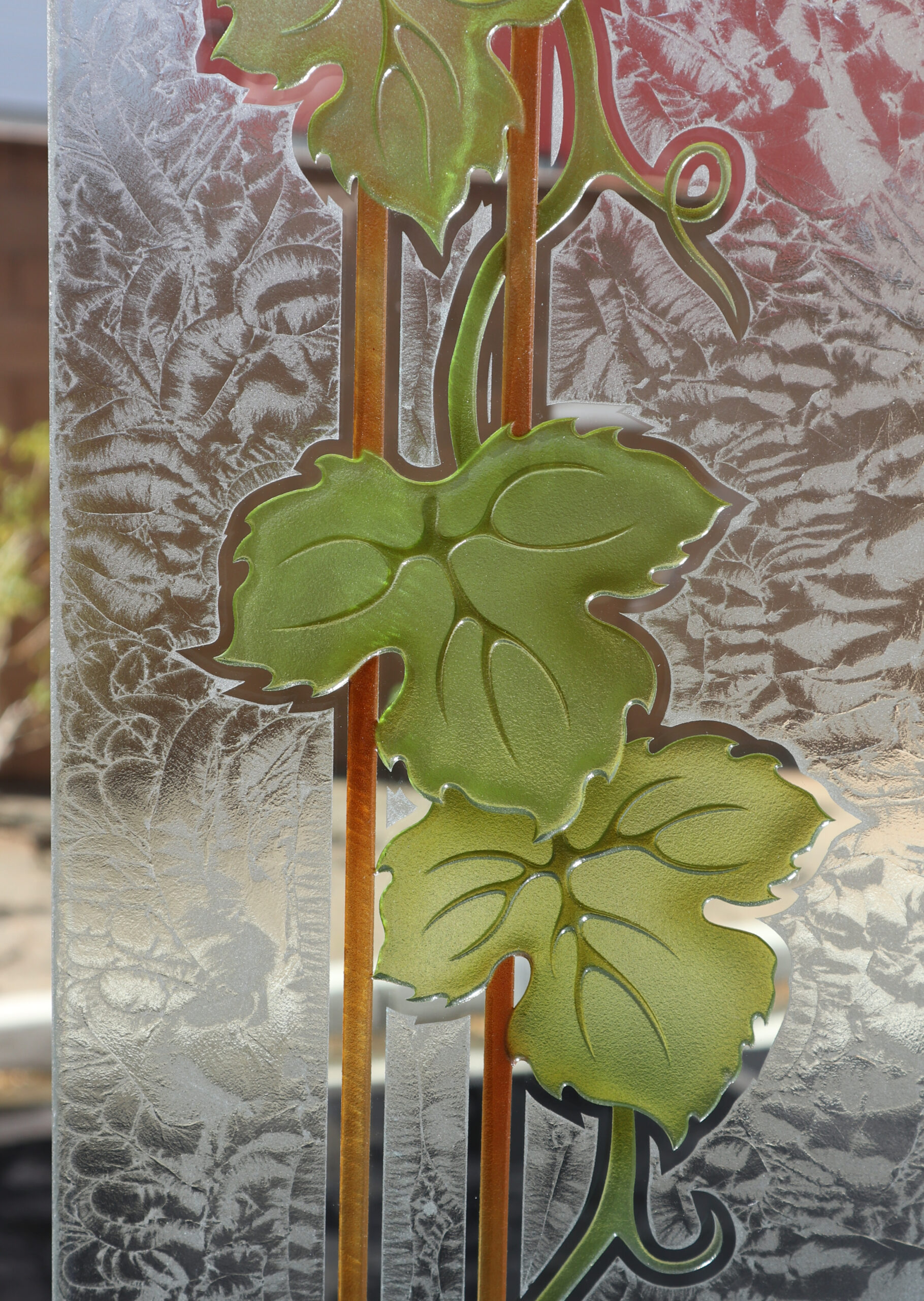 Carved and painted grapevine leaves with vertical vine accents on frosted glass.