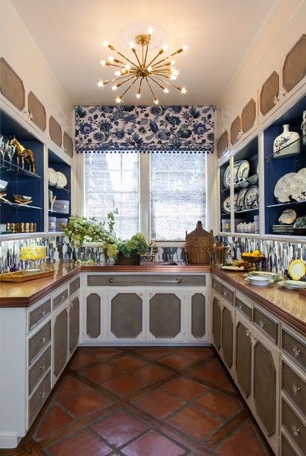 Terra-cotta floors, decorative paneled cabinets and a mid-century sparkling chandelier butler pantry