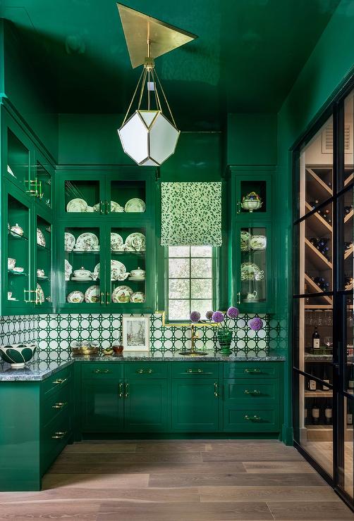 Emerald green butler's pantry modern brass chandelier glossy emerald green ceiling emerald green lacquer cabinets with lucite pulls cabinets with gray marble countertop white and green lattice backsplash tiles under stacked glass front upper cabinets with round brass sink 
