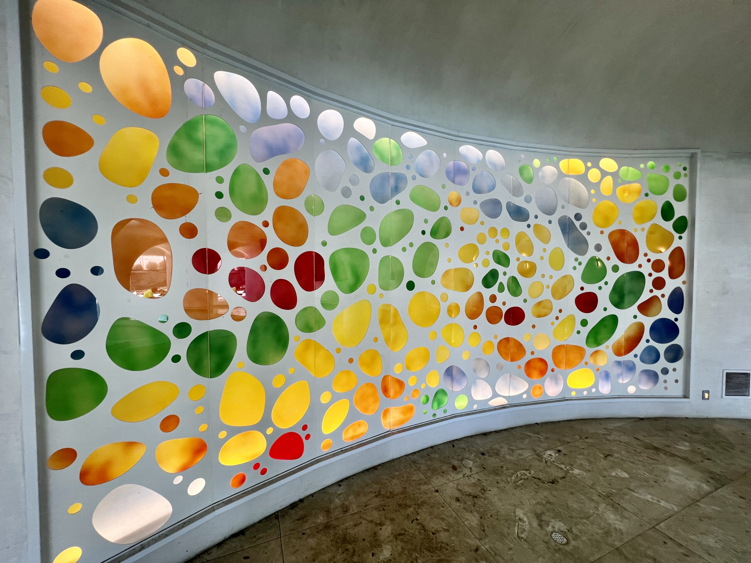 Large curved decorative frosted glass wall with colorful abstract design as architectural feature