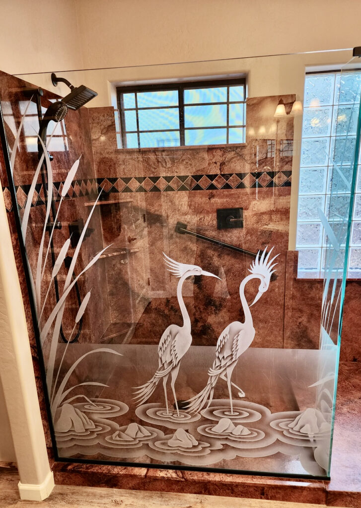 Etched glass shower panel featuring carved cranes standing among cattails with layered privacy frosting
