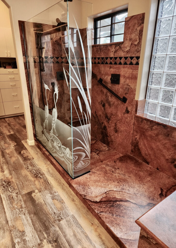 Etched glass shower enclosure with carved crane scene and cattail detailing