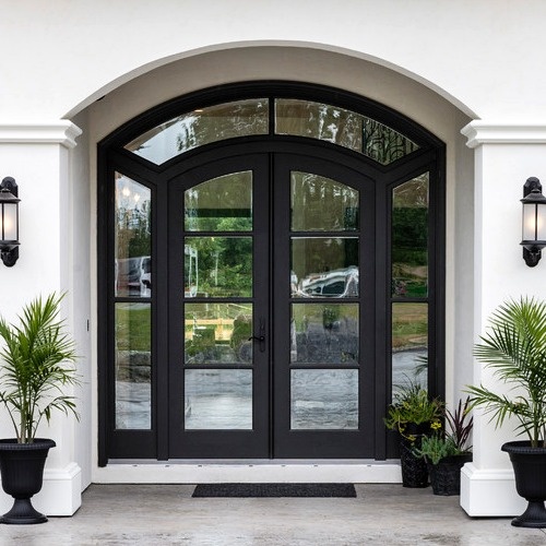 Arched black steel entry doors with large glass panels on white exterior