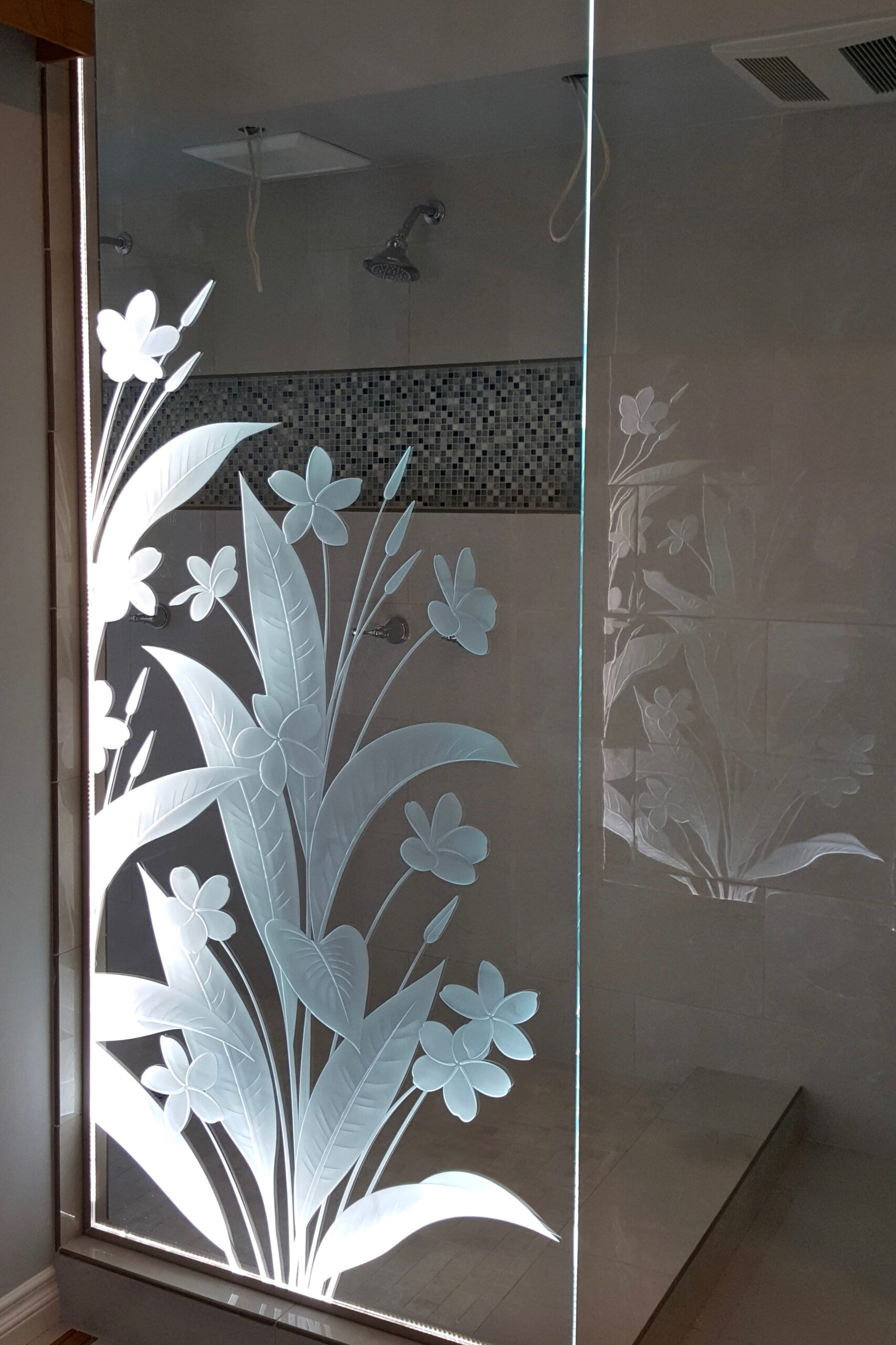 Frosted glass shower panel featuring etched Plumeria floral design – spa-style bathroom setting by Sans Soucie Art Glass