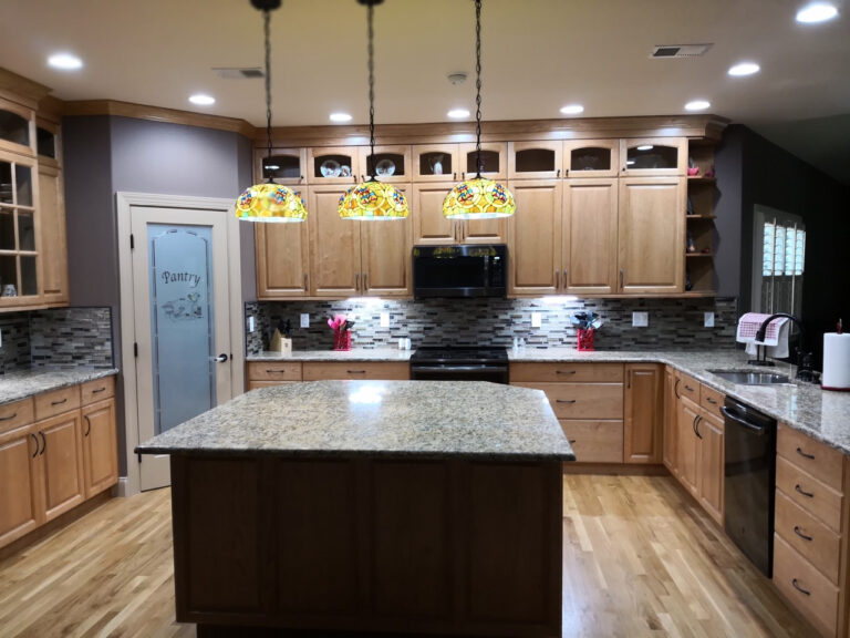 Corner pantry with frosted glass pantry door, nestled in a kitchen with brown cabinets, granite countertops, and warm wooden floors.