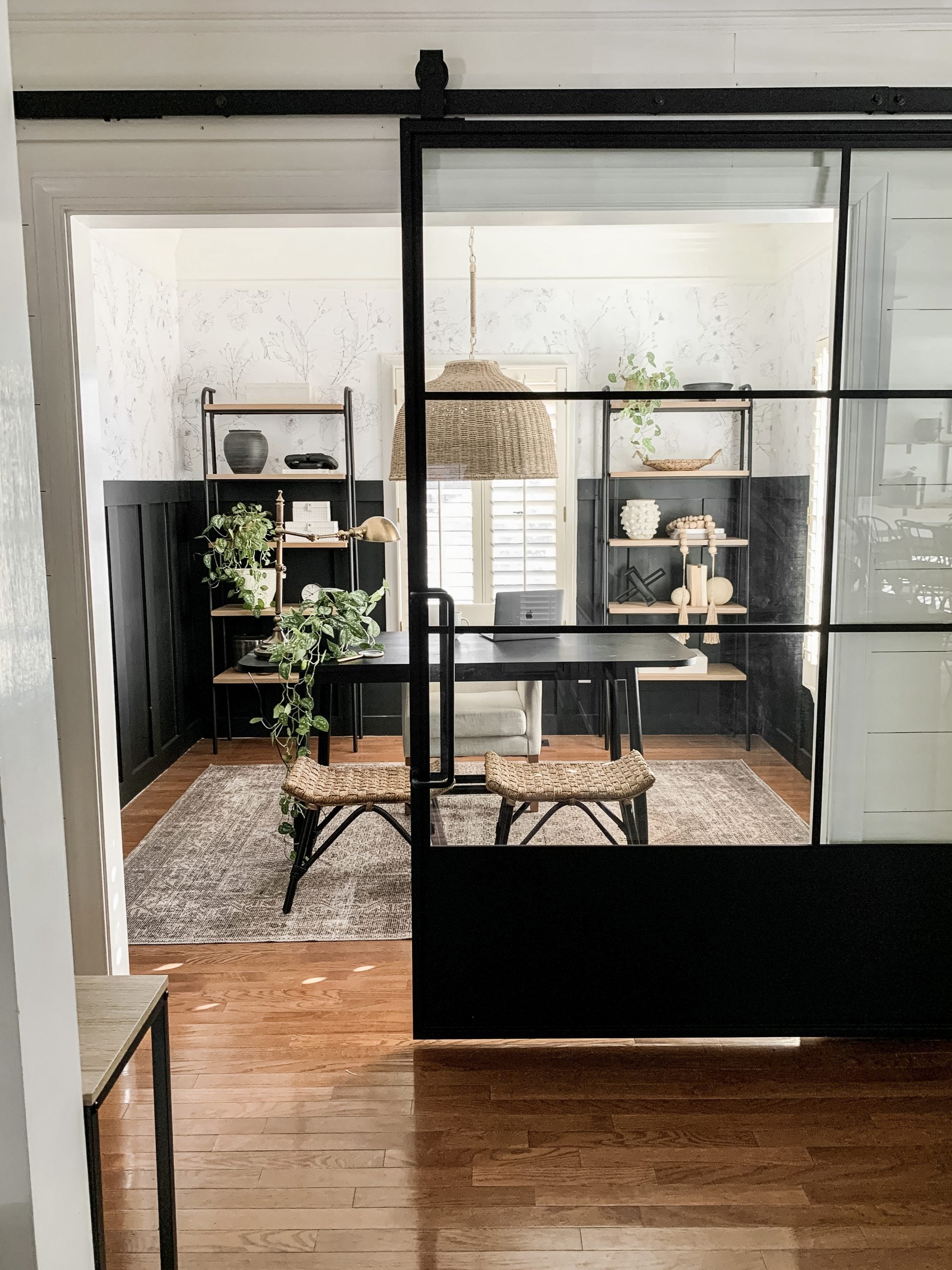 Contemporary glass barn door with black steel frame separating a home office workspace