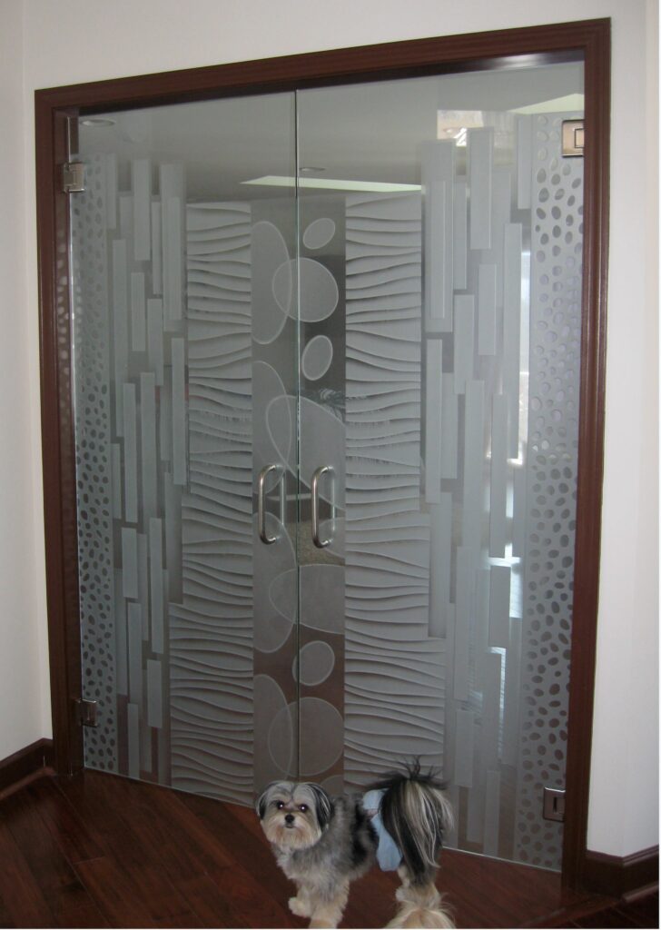 Etched glass interior double doors with geometric etched design provide privacy while allowing natural light, with a small dog standing in front