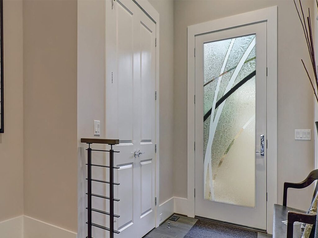 Semi-private front door with glass inserts and gluechip finish, demonstrating how frosted glass doors look at night with interior lighting &mdash; durable glass doors backed by decades of craftsmanship.