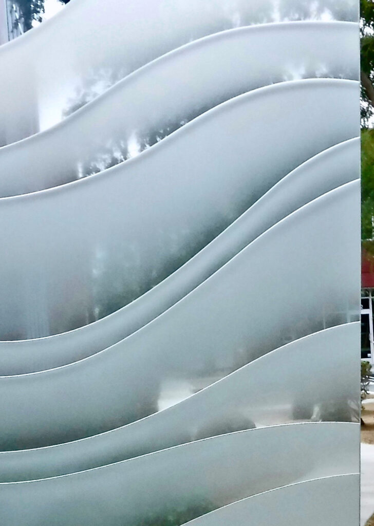 Close-up of 3D carved clear glass waves with semi-private privacy and sculpted sandblasted texture