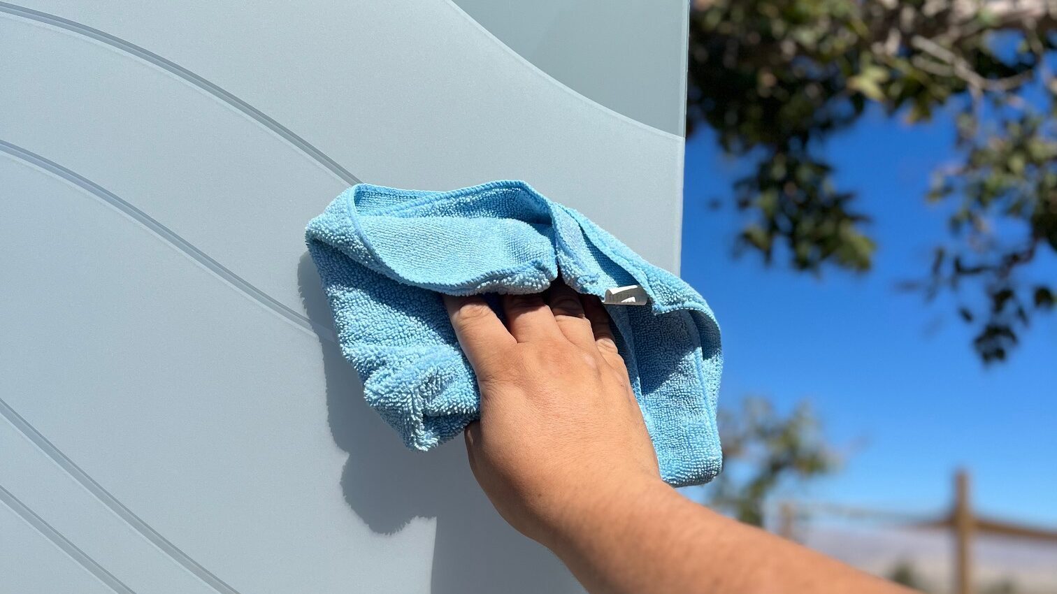 Person cleaning frosted interior glass door with microfiber cloth.