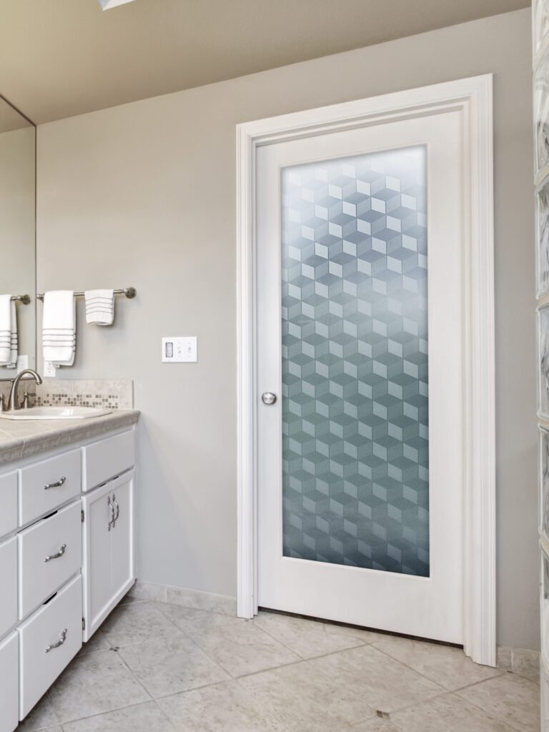 Frosted glass door with geometric cube pattern providing full privacy while allowing soft natural light into the bathroom