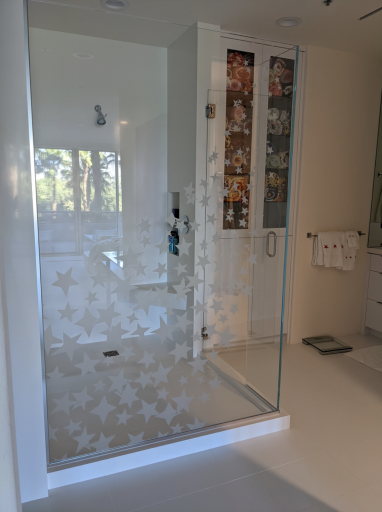 Frameless corner shower enclosure with frosted glass star pattern etched into clear glass panels