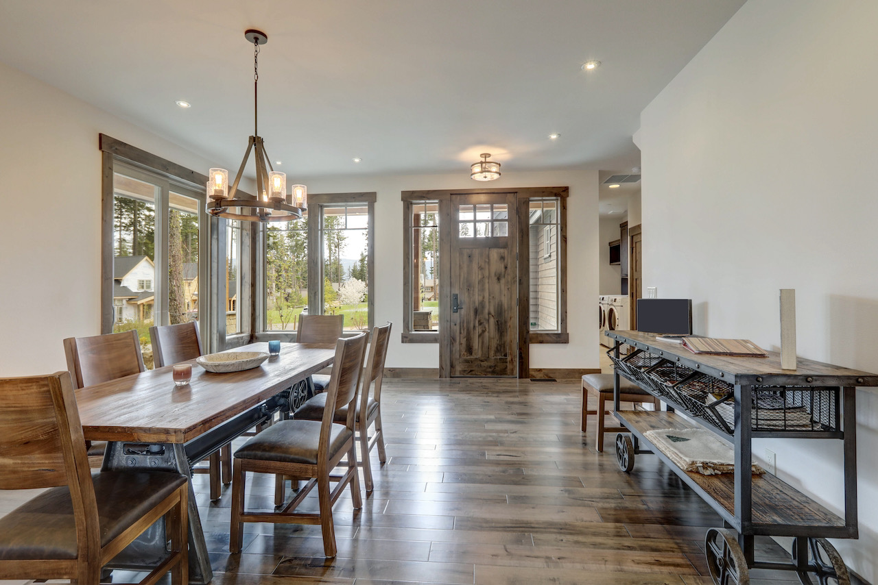 Rustic modern farmhouse front door with glass panels in a bright entryway beside a dining room with wood floors and natural trim