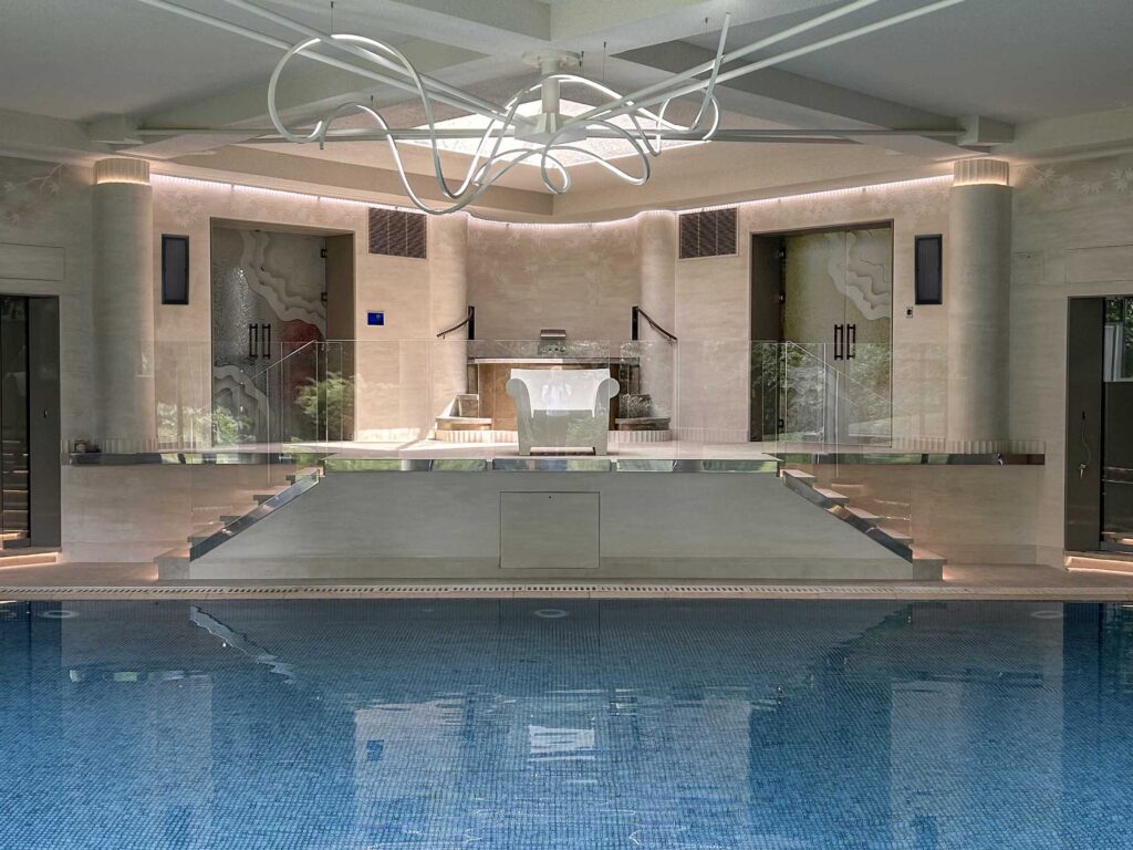 Decorative frosted glass doors with etched organic wave pattern in a luxury spa pool area with modern architectural lighting and glass railings