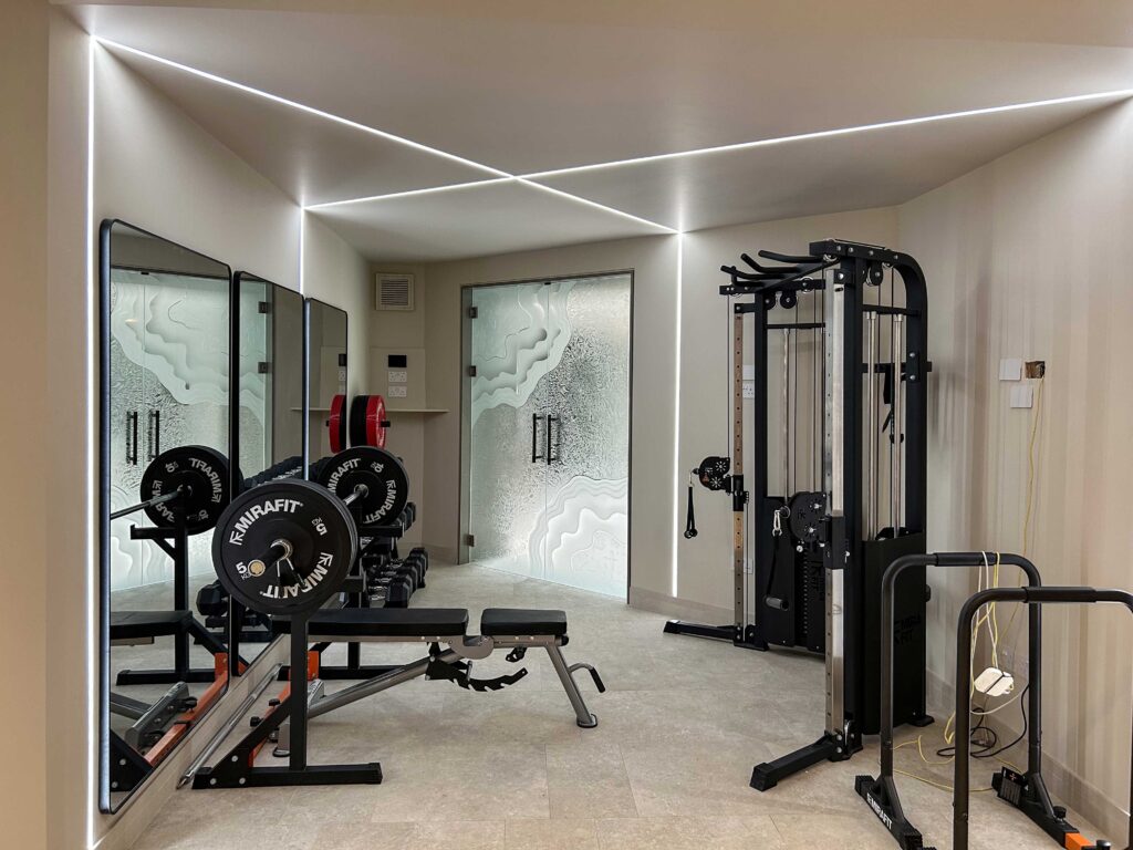 Decorative frosted glass interior doors with custom etched wave design in a modern home gym with mirrored walls and workout equipment