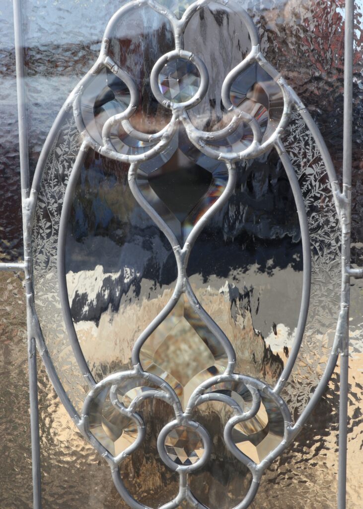 Traditional oval beveled glass design with crystal bevel jewels and textured privacy glass background
