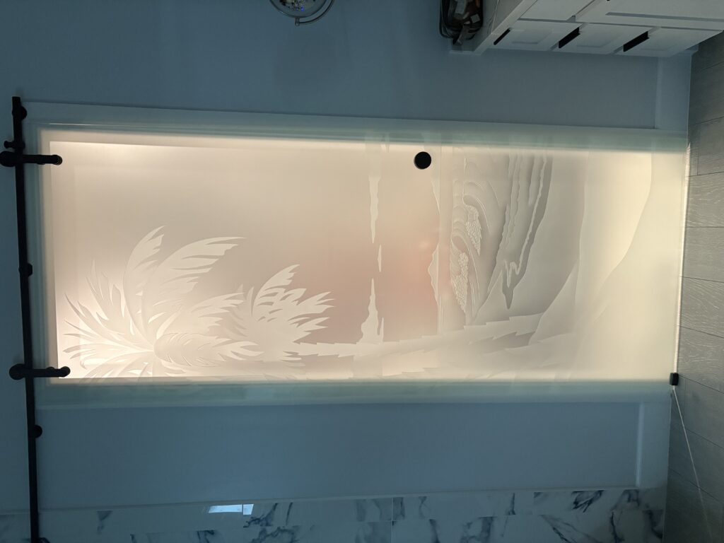 Backlit frosted glass barn door with palm tree design glowing brightly with illuminated etched glass and enhanced privacy