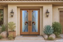 Clear-varnished oak double front doors with frosted glass design featuring abstract swirl and moon designs on a traditional Palm Desert home exterior.
