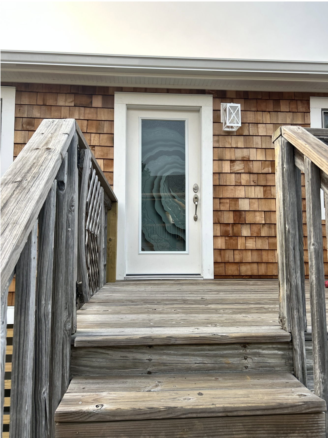 White front door with custom etched glass featuring flowing abstract wave design in coastal style entry exterior