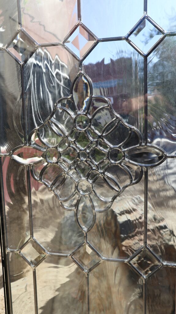 Decorative beveled glass door panel featuring geometric diamond bevels and ornate center cluster in clear leaded glass