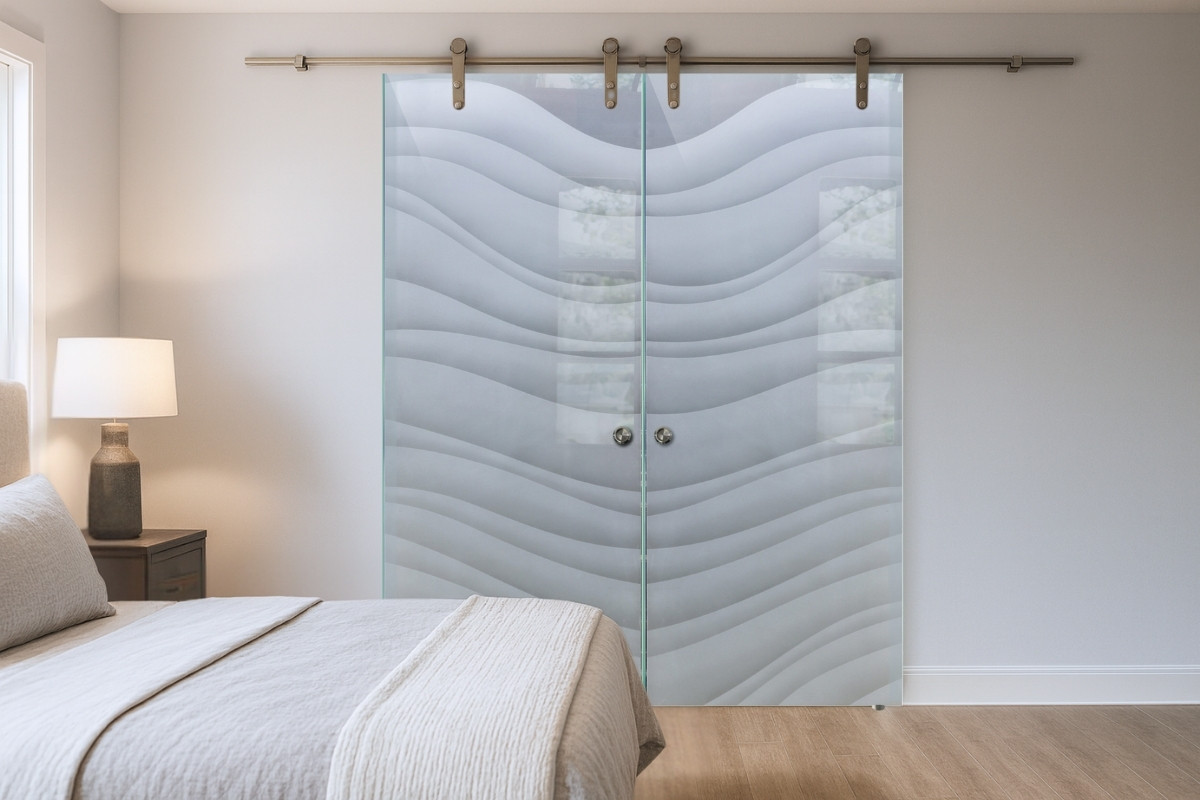 Master bedroom with a walk-in closet divided by sliding double glass barn doors featuring frosted wave design panels.