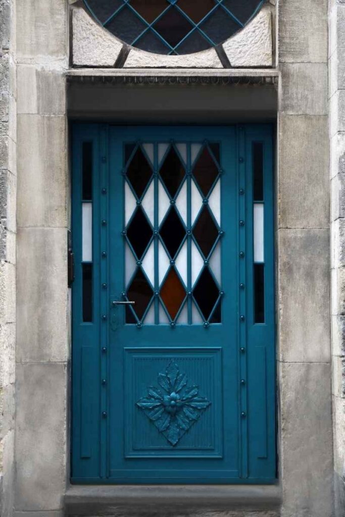 Blue front door with diamond-patterned decorative glass panels and sculpted detailing, inspiring elegant door art ideas for entryways.