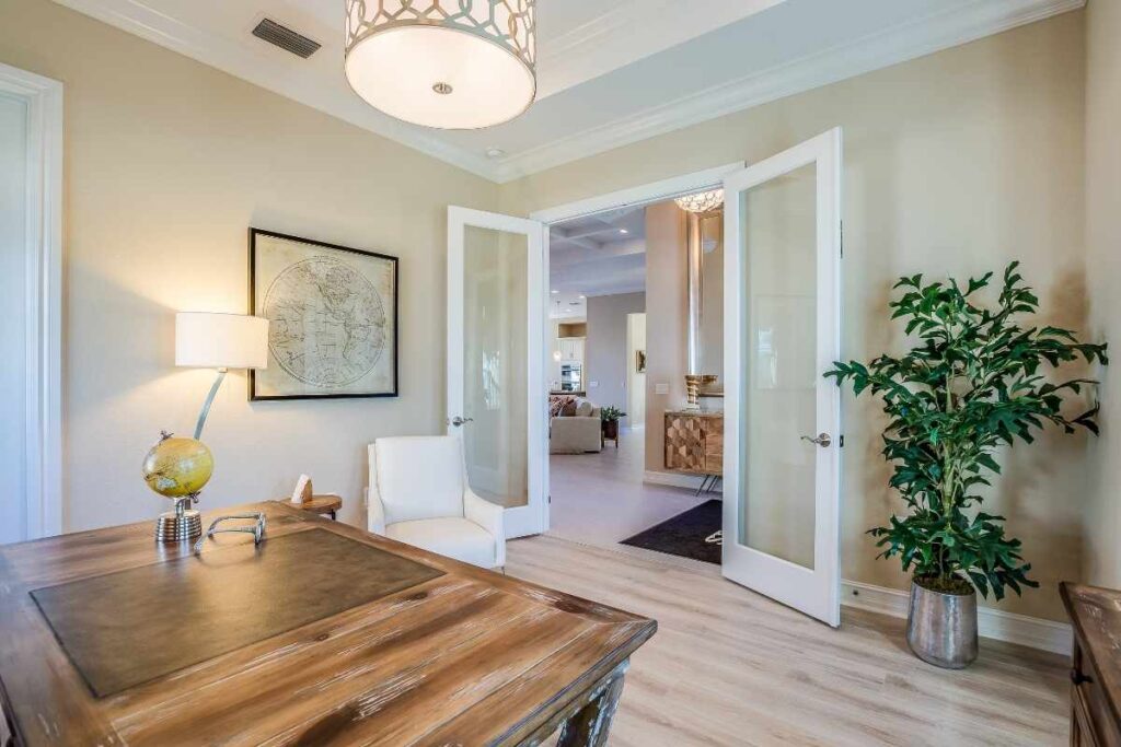 Bright home office with a wooden desk and white French-style frosted glass doors that connect the workspace to adjacent living areas while maintaining privacy.