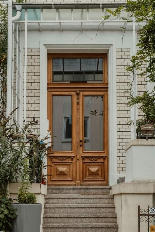 A wooden carved door with a glass window and steps