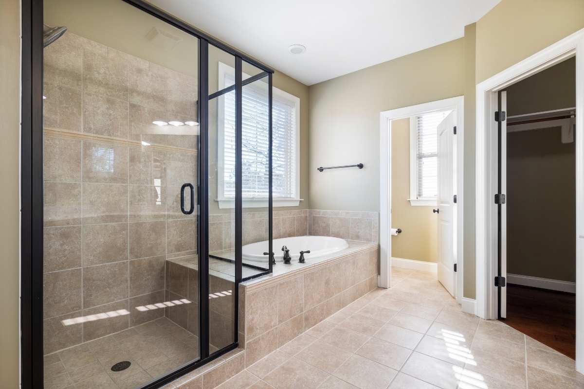White-ceramic bathtub near black framed glass shower door