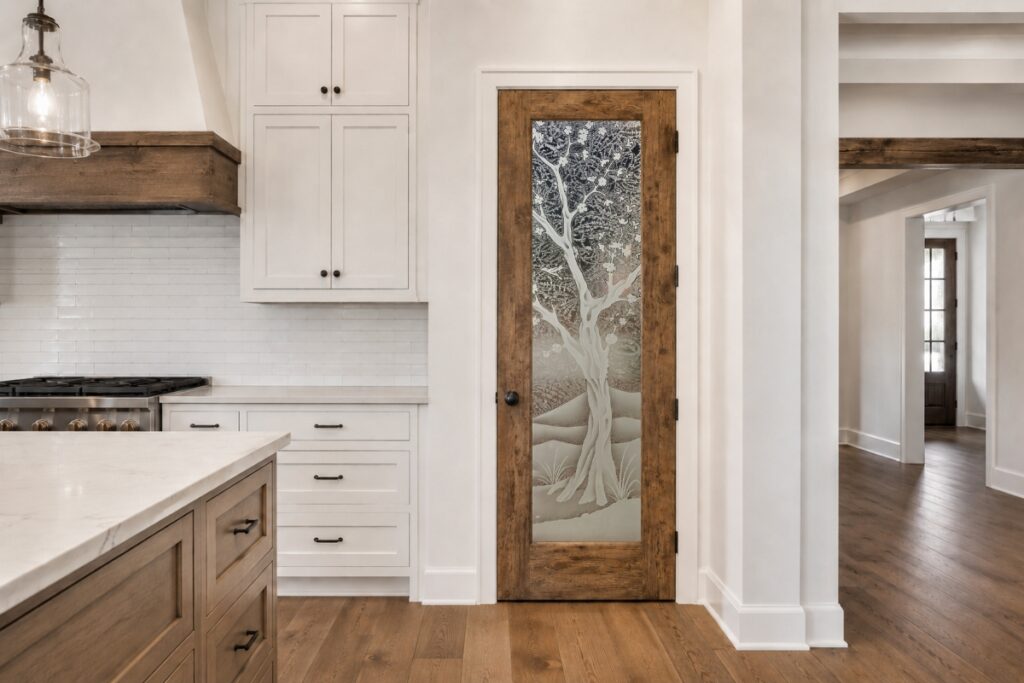 Modern farmhouse kitchen featuring a rustic wood framed frosted glass pantry door with a carved cherry blossom tree design