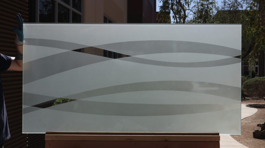 Custom decorative frosted glass panel with flowing wave accents sandblasted into the glass, creating permanent privacy without window film