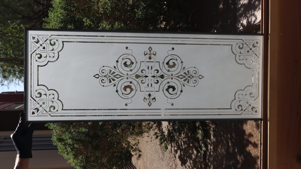 Frosted glass panel with an elegant etched scrollwork design, illustrating the refined appearance and privacy benefits of acid-etched glass