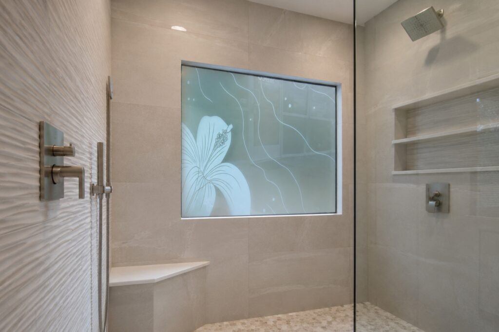 Shower with picture window featuring frosted hibiscus decorative glass in a clean modern walk-in shower with neutral tile and spa-inspired design.